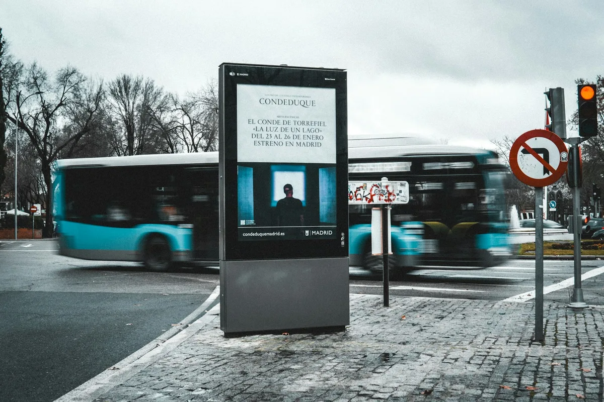 Totem d'affichage numérique extérieur en bord de rue, sur un trottoir mouillé