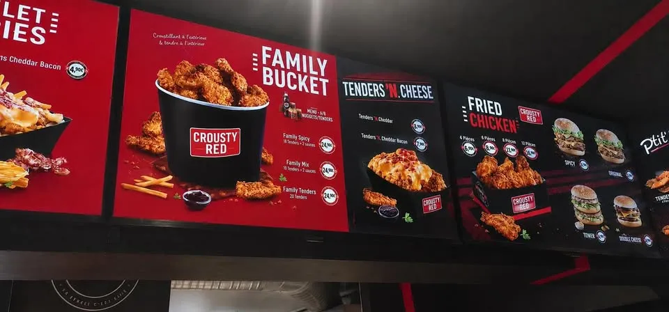Deux écrans LED menu board installés au-dessus du comptoir d'un fast-food hot dog et nuggets