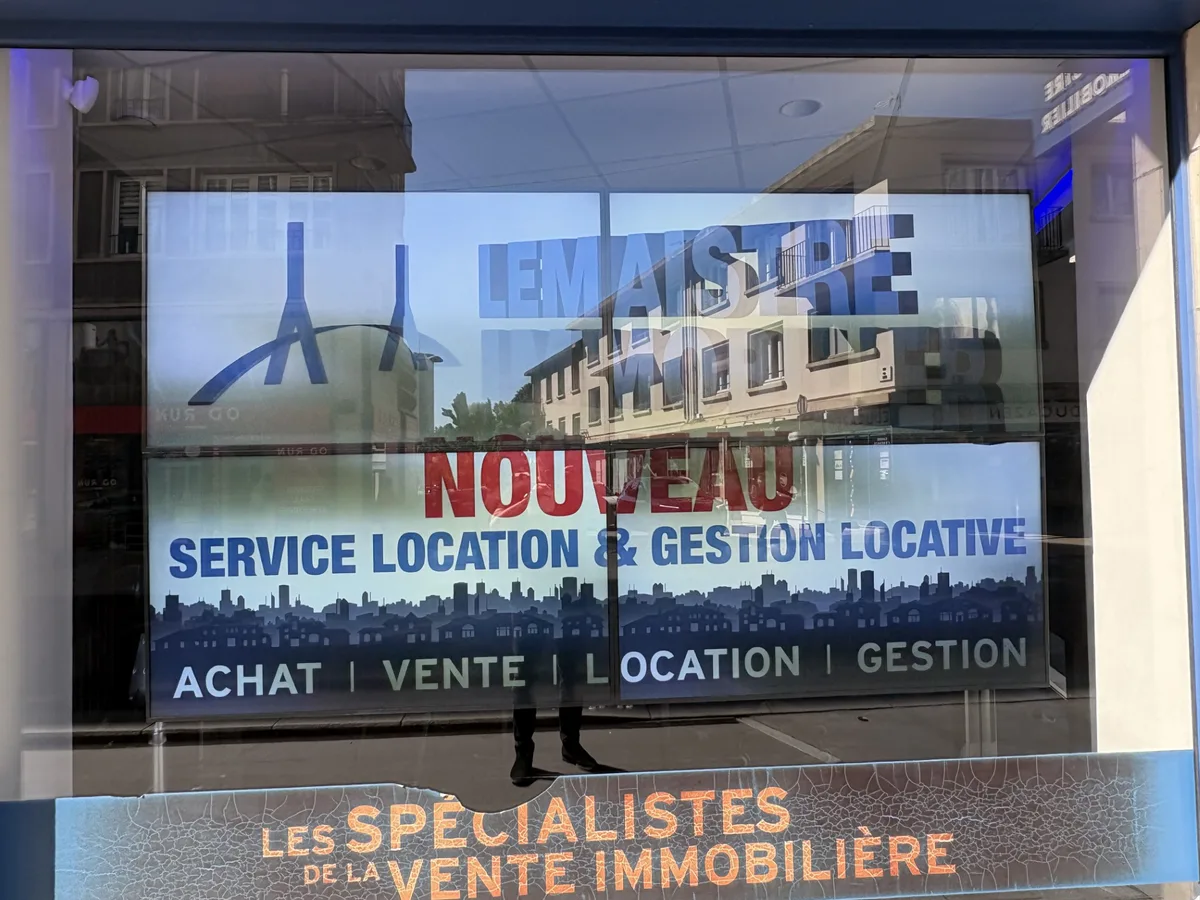 Grand écran LED en vitrine d'une agence immobilière annonçant un service de location et gestion locative