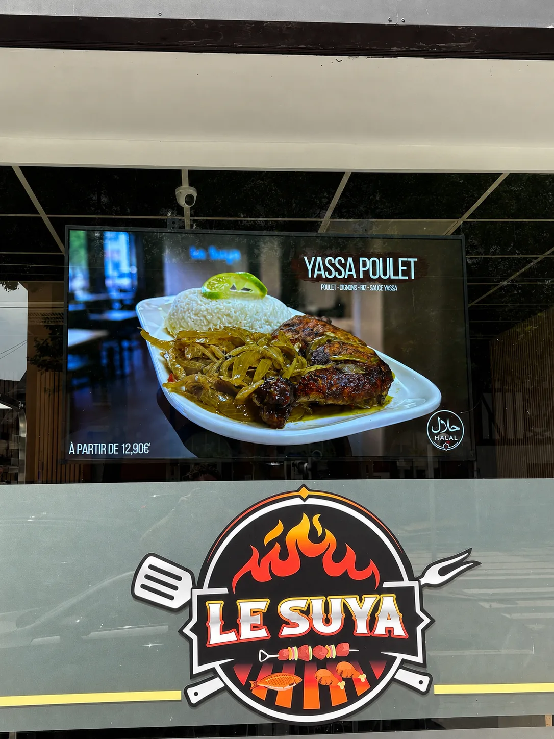 Écran extérieur sous auvent d'un restaurant affichant un plat en grand format au-dessus de l'enseigne