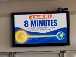 Écran extérieur fixé au mur d'un collège, affichant une rubrique « Le savais-tu ? » sur la lumière du Soleil