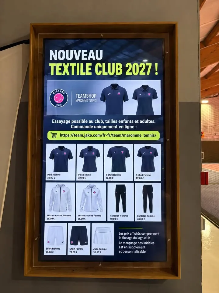 Écran vertical encadré de bois dans un club de tennis, à côté des courts couverts, présentant la nouvelle collection textile du club